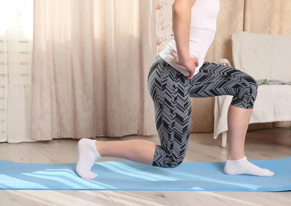 Onherkenbaar vrouw doen fitness oefening thuis op een blauwe mat in woonkamer, squats doen. benen en lichaam — Stockfoto