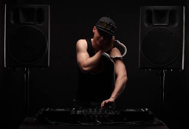 Kulüp Dj beyaz kulaklık partide müzik ile. arka plan üzerinde büyük hoparlörler.