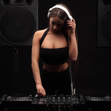 Genç seksi brutette kadın dj beyaz kulaklık müzik karıştırıcı masada oynarken uzun saçlı.