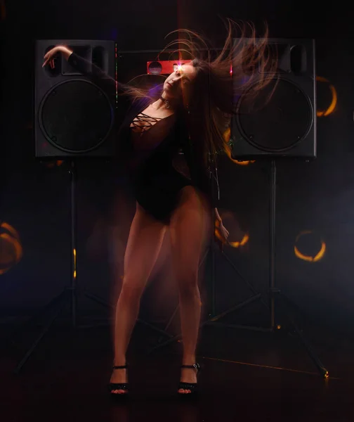 Sexy chica joven con el cuerpo perfecto y piernas largas danza gogo cerca de dos grandes altavoces negros. técnica de flash de sincronización lenta — Foto de Stock