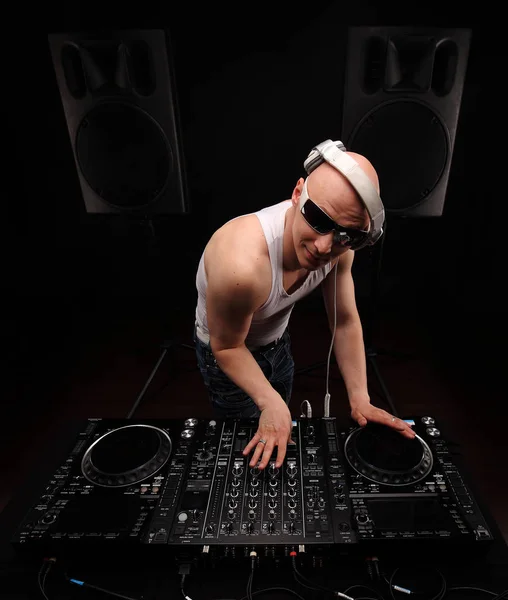 Homem DJ em camisa branca tocar música no mixer de um DJ. Tiro no estúdio. Fundo escuro com alto-falantes grandes — Fotografia de Stock