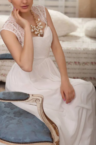 Esküvő előkészítés. Gyönyörű fiatal menyasszony, fehér menyasszonyi ruha bent Vértes. Luxus modell vintage szék otthoni stúdióban ül — Stock Fotó
