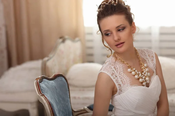 Wedding preparation. Beautiful young bride in white wedding dress indoors. — Stock Photo, Image