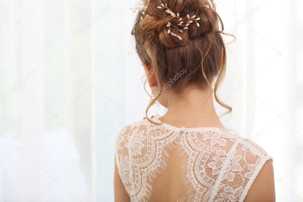 Tender wedding stylish hairstyle , Elegant brunette bride standing back with collected up do hair. Light bridal morning preparation.