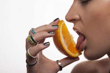 Kız narin elleri üzerinde bir portakal, kolye ve yüzük yala. Takı reklam. beyaz izole.