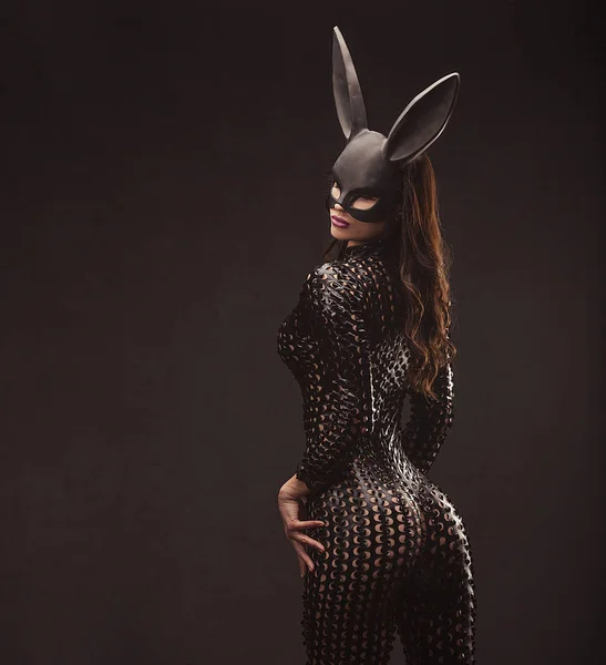Retrato de mulher morena sexy posando em coelho máscara preta e bodysuit de volta tiro — Fotografia de Stock