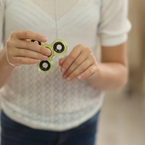 Niño jugando con verde fidget spinner primer plano manos en habitación luminosa — Foto de Stock