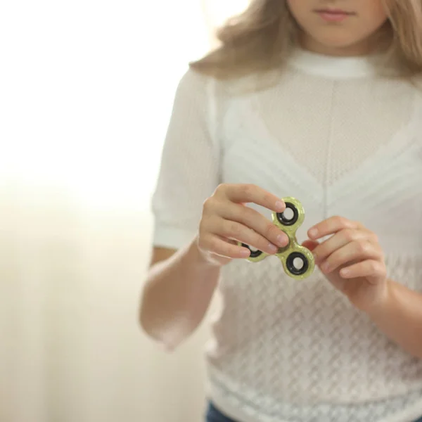 Dziewczynka w białej koszuli, grając z fidget zielony spinner w jasny pokój — Zdjęcie stockowe