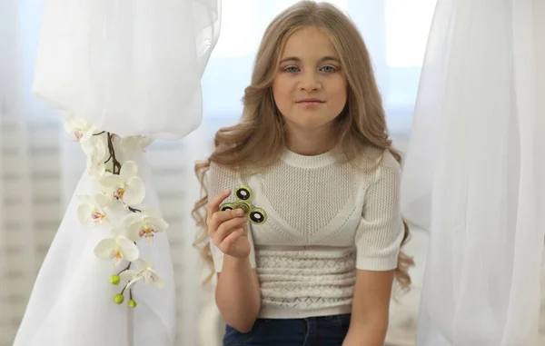 Menina bonito jogando com fidget spinner no quarto brilhante Fotos De Bancos De Imagens