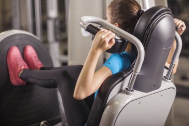 Genç kadın bacak basın bir fitness merkezi yerleştirmek. Fitness salonunda, yaşam kavramı kız portresi.