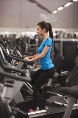 kardiyo bir fitness merkezinde bir bisiklet kullanan kadın uygun. Spor salonunda fitness kız portresi.