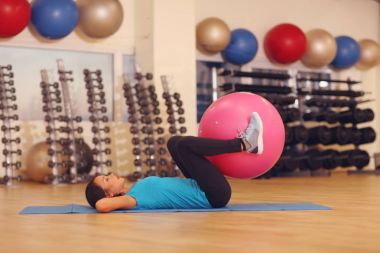 Kadın fitness beden eğitimi dersinde pembe uygun topu ile yapıyor. Fitness topu bir tonda, sıkı mide ve güçlü çekirdek kadın yardımcı olur. Sağlıklı yaşam kavramı