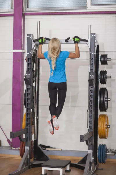 Bodybuilding. Strong fit woman exercising in a gym - doing pull-ups.. — Stock Photo, Image