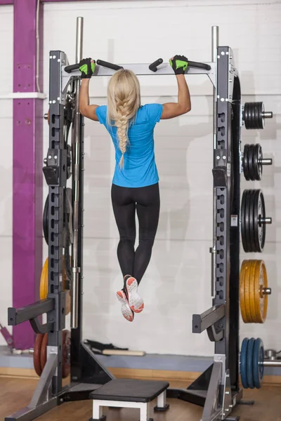 Bodybuilding. Strong fit woman exercising in a gym - doing pull-ups. — Stock Photo, Image