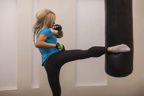 Mladá dívka dělá boxerský trénink v tělocvičně. Žena bojovník smash boxovací pytel — Stock fotografie