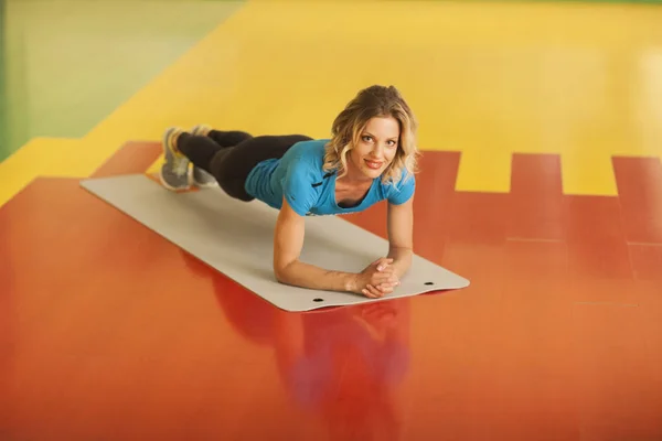 Culturismo. mujer haciendo ejercicio en la estera en clase de fitness. Entrenamiento femenino en gimnasio haciendo tablón —  Fotos de Stock