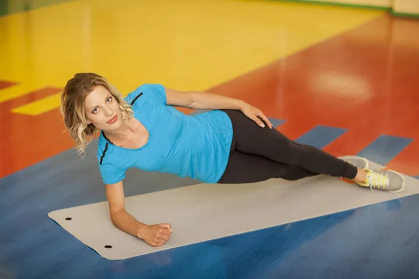 Culturismo. donna che si allena sul tappeto in classe di fitness. Allenamento femminile in palestra facendo tavola — Foto Stock
