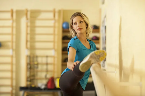 Allungamento femminile in classe fitness colorato con corrimano — Foto Stock