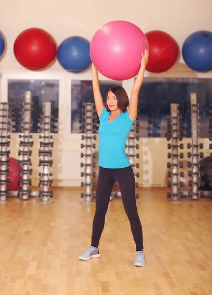 Kvinnan gör övningar med rosa passar bollen i fitness gym klass. Fitness boll hjälper kvinnor få en tonad, tight mage och stark kärna. Begreppet hälsosam livsstil — Stockfoto