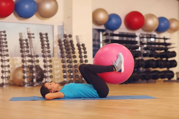 Kobieta robi ćwiczenia z różowy piłka fit fitness siłownia klasy. Piłka fitness pomaga kobietom uzyskać stonowanych, napięty brzuch i zdecydowanego. Pojęcie zdrowego stylu życia — Zdjęcie stockowe