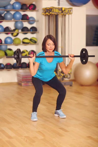 Bodybuilding. kvinna som tränar med skivstång i fitness klass. Kvinnliga träningspass i gymmet göra knäböj med vikt. — Stockfoto