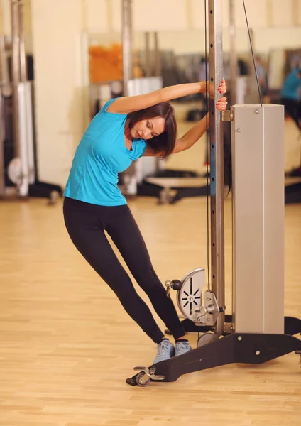 Mujer joven en el gimnasio haciendo ejercicio en una máquina —  Fotos de Stock