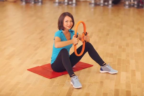 Magie pilates anneau femme aérobic sport gymnase exercices sur le sol, souriant et regardant à la caméra . — Photo