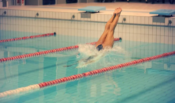 Egy női úszó, hogy jumping és a búvárkodás a fedett uszoda. Sportos nő. — Stock Fotó