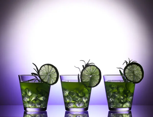 Stillleben mit bunten, hellen Cocktails auf Glas, dekoriert mit Rosmarin und Limette — Stockfoto