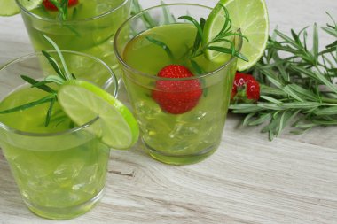 Biberiye, çilek ve kireç ile dekore edilmiş ahşap arka plan üzerinde renkli parlak kokteyller ile natürmort