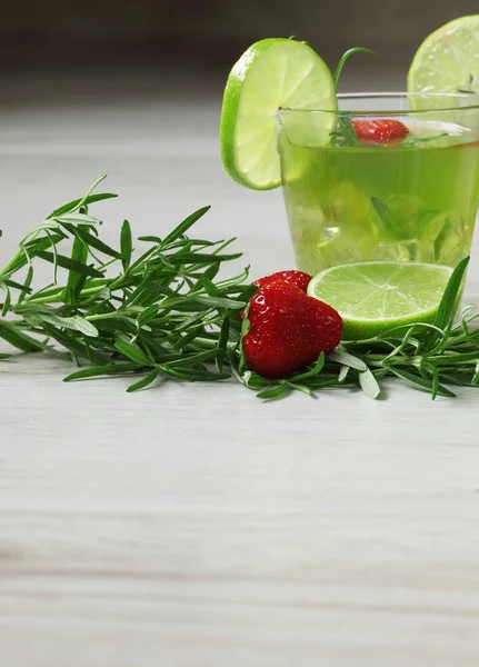 Cocktail verde su fondo legno, decorato con rosmarino, fragola e lime — Foto Stock