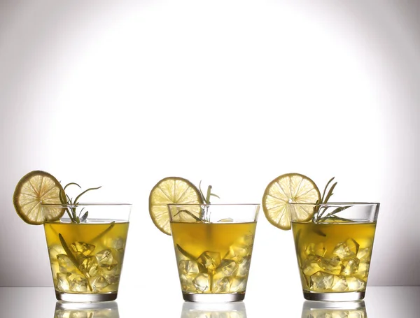 Drei gelbe Cocktails mit Zitrone und Rosmarin stehen auf Glas im Studio — Stockfoto