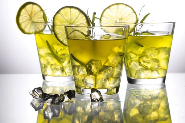 Tre cocktail gialli con limone e rosmarino in piedi su vetro in studio — Foto Stock