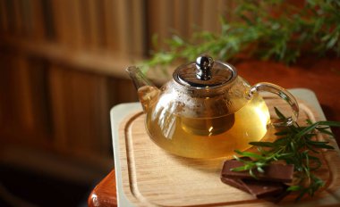 Biberiye ve çikolata yakınındaki, arka plan, ev rahat iç kitap ile ahşap kesme tahtası üzerinde bitki çayı ile çaydanlık