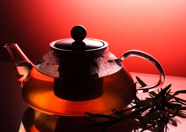 Teekanne mit Kräutertee, Rosmarin in der Nähe, Studioaufnahme beleuchtet mit Rot — Stockfoto