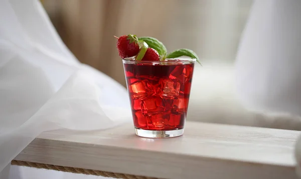 Roter Cocktail mit Eis, dekoriert mit Minzblatt, Limette und Schleppbeere auf hellem Hintergrund — Stockfoto