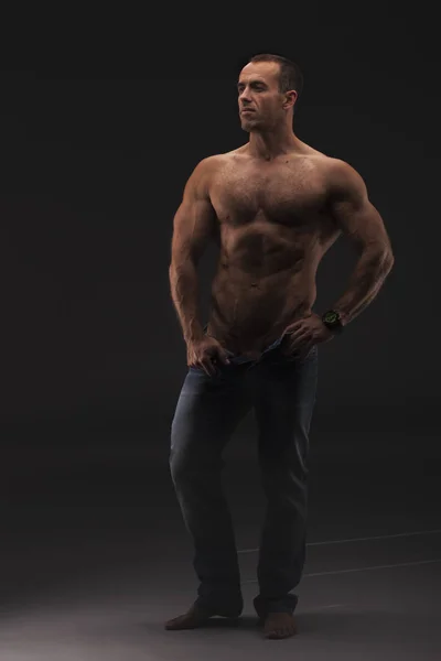 Ισχυρή αθλητικό κορμό μοντέλο Fitness άνθρωπος δείχνει έξι pack abs. μισό γυμνό αρσενικό το μοντέλο στο ξεκούμπωτο τζιν. Studio γυρίσματα — Φωτογραφία Αρχείου
