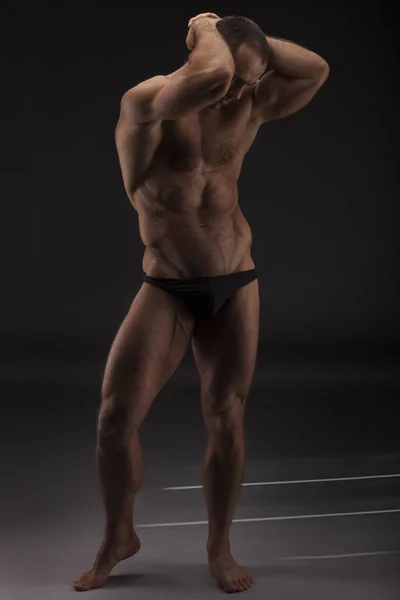 Retrato sexy de un modelo masculino sin camisa muy musculoso en ropa interior negra sobre fondo gris de estudio —  Fotos de Stock
