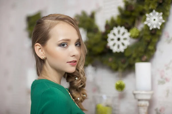 Hermosa modelo de moda con vestido verde en el estudio en el fondo iluminado con verde. Navidad — Foto de Stock