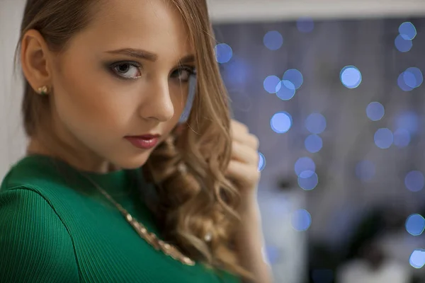 Hermosa modelo de moda con vestido verde en el estudio en el fondo iluminado con verde. Navidad — Foto de Stock