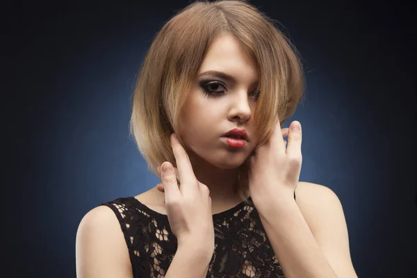 Vacker modell bär svart aftonklänning som går på catwalken i studio på bakgrunden belyst med blått. Aggressove ser, röda läppar och bara ena ögat. — Stockfoto