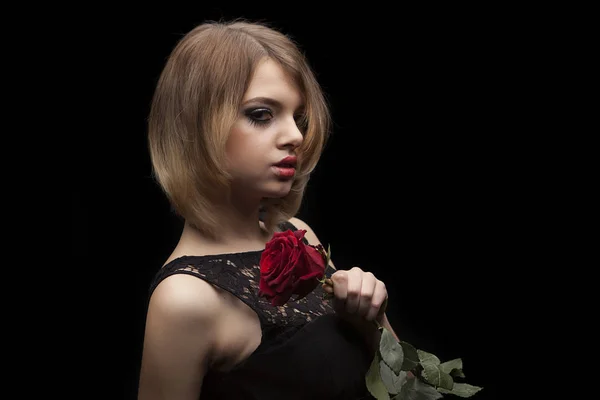 Hermosa modelo de moda con vestido de noche negro caminando en la pasarela en el estudio en el fondo iluminado con azul. Mirada agresiva, labios rojos y un solo ojo . — Foto de Stock