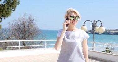 Güzel sarışın beyaz kadın cep telefonuyla konuşurken gülümseyerek. İtalyan sahil şeridi.