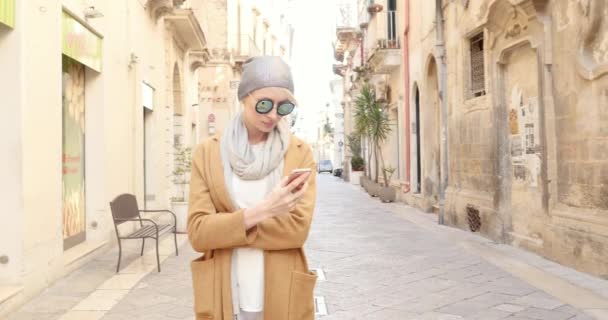 Bella giovane donna caucasica che scrive su smartphone, passeggia in città in Italia . — Video Stock