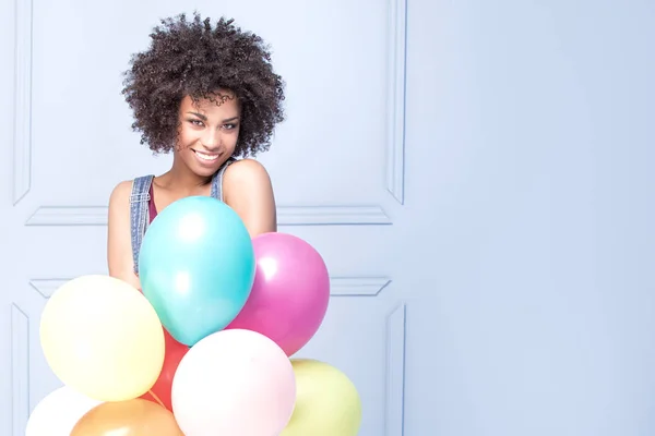 Glad ung flicka med afro holding ballonger. — Stockfoto