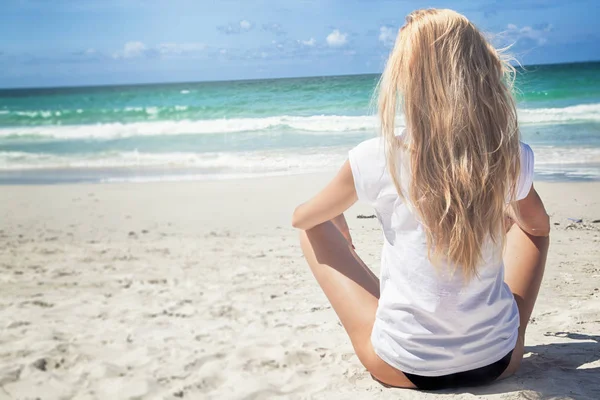 Молода блондинка сидить на пляжі — стокове фото