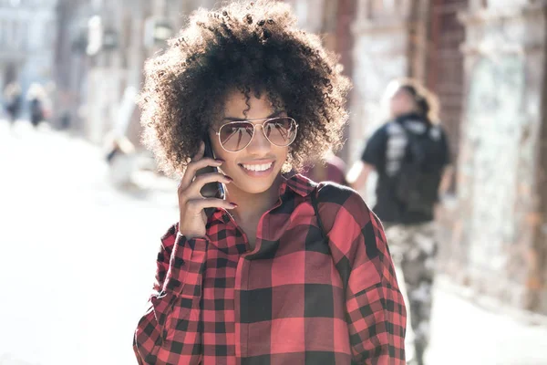 Дівчина з зачіскою на афро за допомогою смартфона . — стокове фото