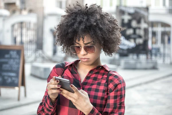 Mädchen mit Afro-Frisur mit Smartphone. — Stockfoto