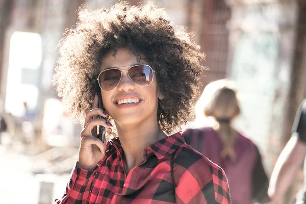 Flicka med afro frisyr med hjälp av smartphone. — Stockfoto