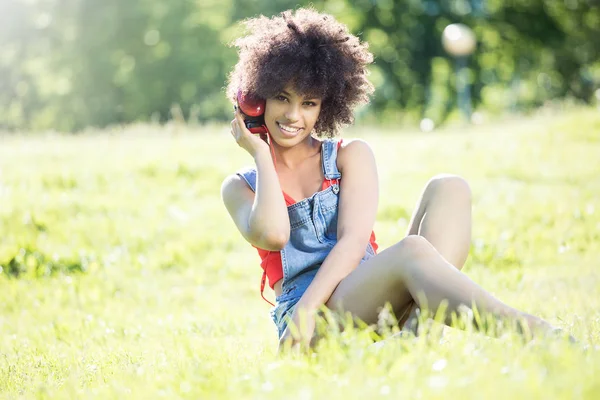 Africana chica americana relajante al aire libre con auriculares . — Foto de Stock